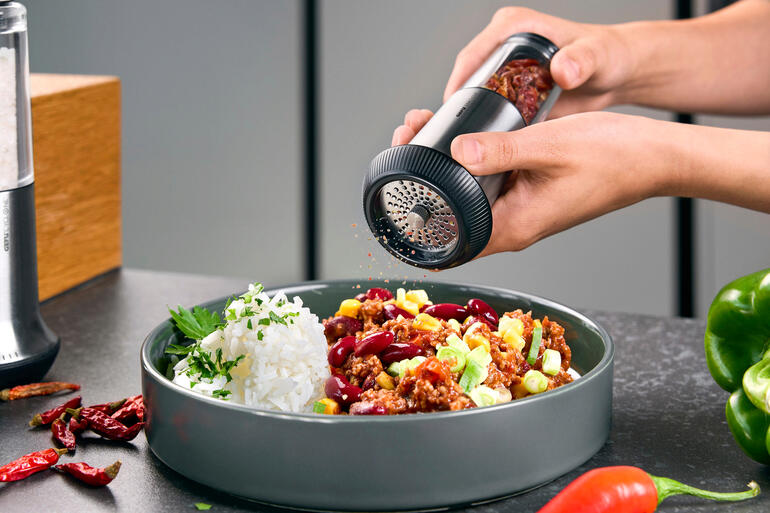 Chili-snijden X-Plosion® wordt boven een bord met rijst en groenten gehouden