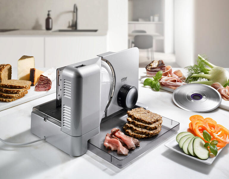 Allesschneider Duo Plus snijdt brood en vleeswaren op een aanrecht.