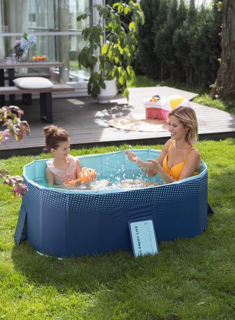 Opblaasbaar zwembad met moeder en kind in het water, omgeven door een groen gazon.
