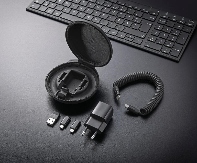 Het harde etui bevat: 30 W GaN-voedingsadapter, USB-C-spiraalkabel (met een laadvermogen tot 60 W) en 1 USB-A-, 1 micro-USB- en 1 Lightning-adapter. All-in-One laadset op een bureau, inclusief kabel en adapters.