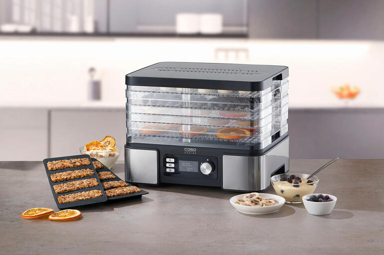 Voedseldroger op een tafel met verschillende gezonde snacks en ingrediënten.
