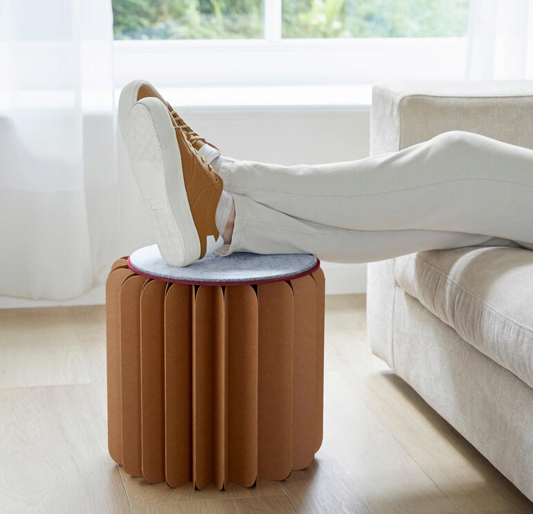 Vrouw met een Bookniture-poef die als voetensteun wordt gebruikt.