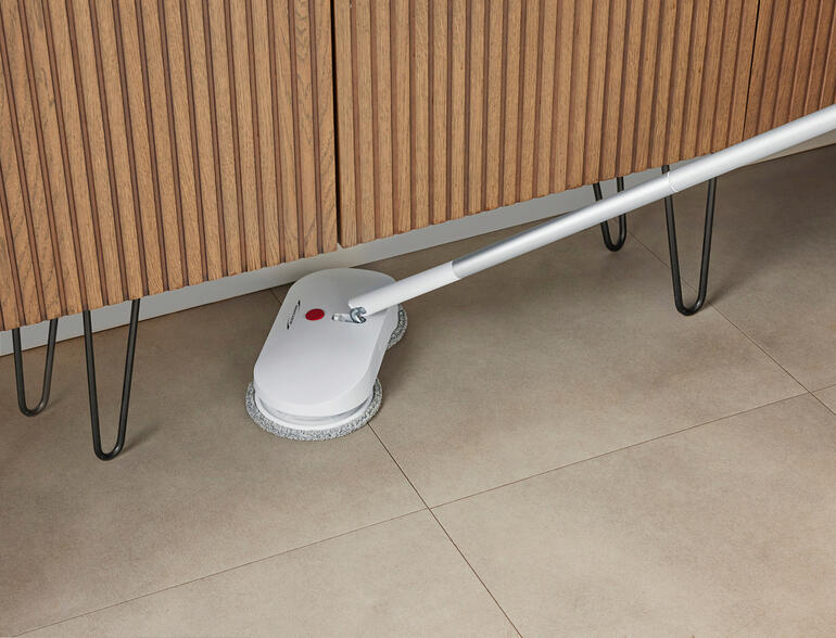 Dankzij de 180° draaibare grijpstang is het veel gemakkelijker om moeilijk te bereiken plekken te reinigen – onder de bank, de commode, kasten enz. Accu-dweil onder een meubelstuk, moeilijk bereikbaar