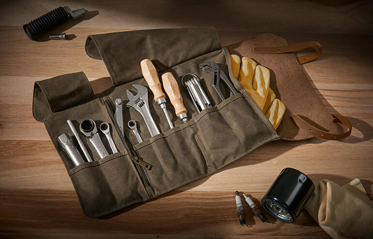 Echtleren gereedschapstas met verschillende gereedschappen op een houten oppervlak