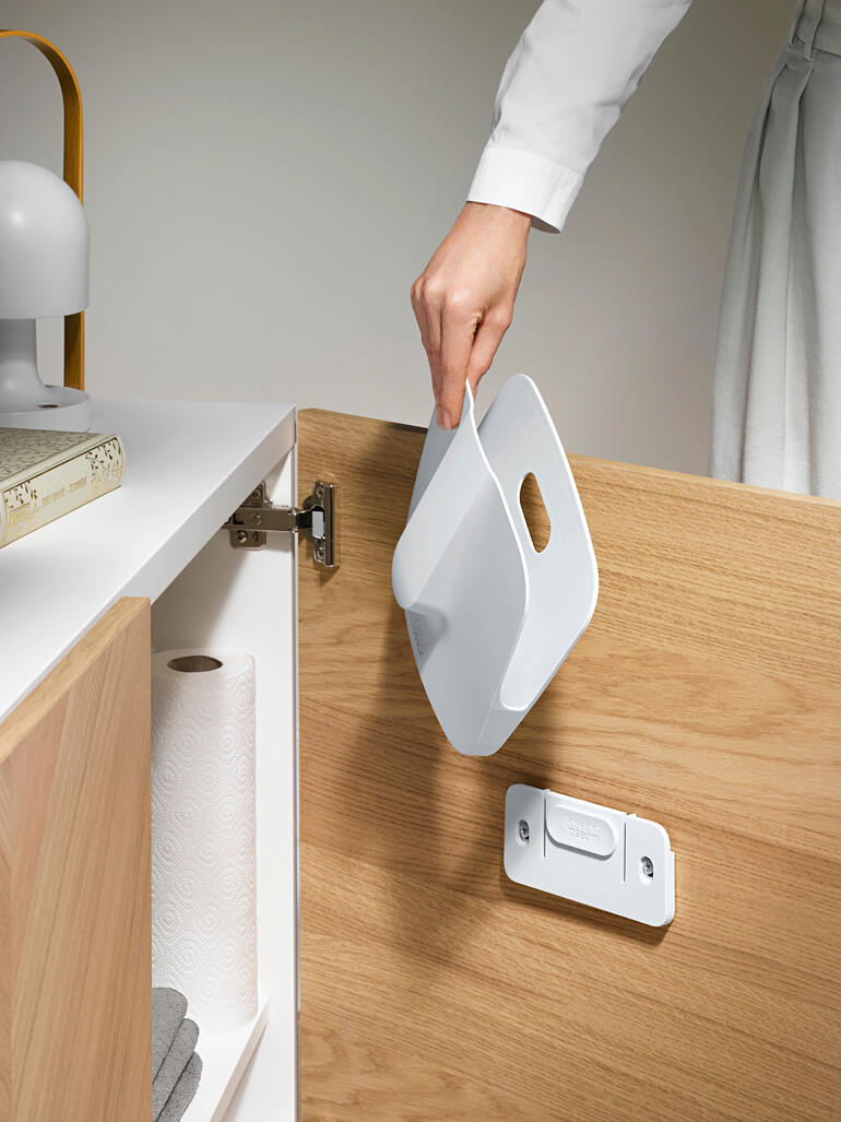 Kruimels of stof die er na gebruik eventueel nog aan blijven hangen, worden opgevangen in de afneembare houder – klaar om te worden weggegooid. Hand met een blik uit een kast voor praktische opslag.
