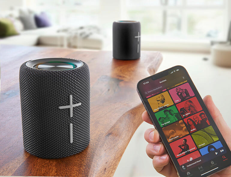 Smartphone toont muziek-streaming-app naast deelbare Bluetooth-luidspreker.