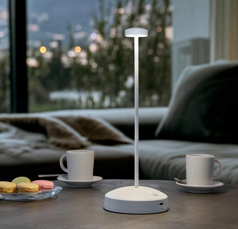 Design tafellamp met batterij, kleur: wit, op een tafel met drankjes.