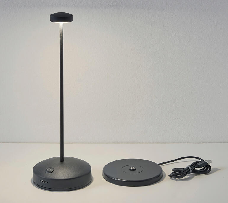 Design tafellamp met batterij in zwart, uitgeschakeld op de tafel.