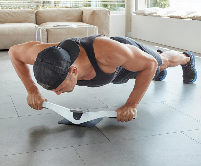 Man voert een plank oefening uit met de Praep® plank trainer op de vloer.