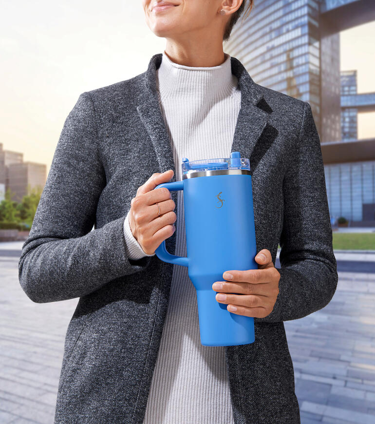 XL Thermos drinkbeker in het blauw, vastgehouden door een persoon in een grijze jas