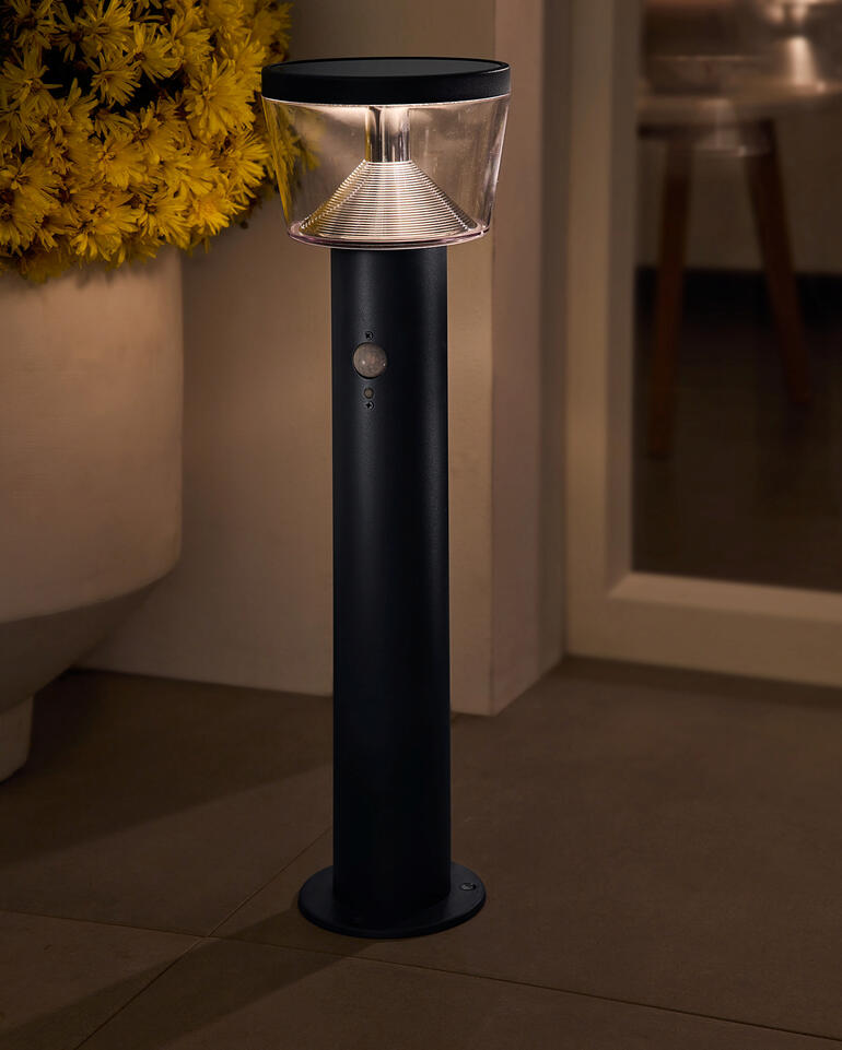 Zonne-lantaarn met een doorzichtige lampenkap in de tuin