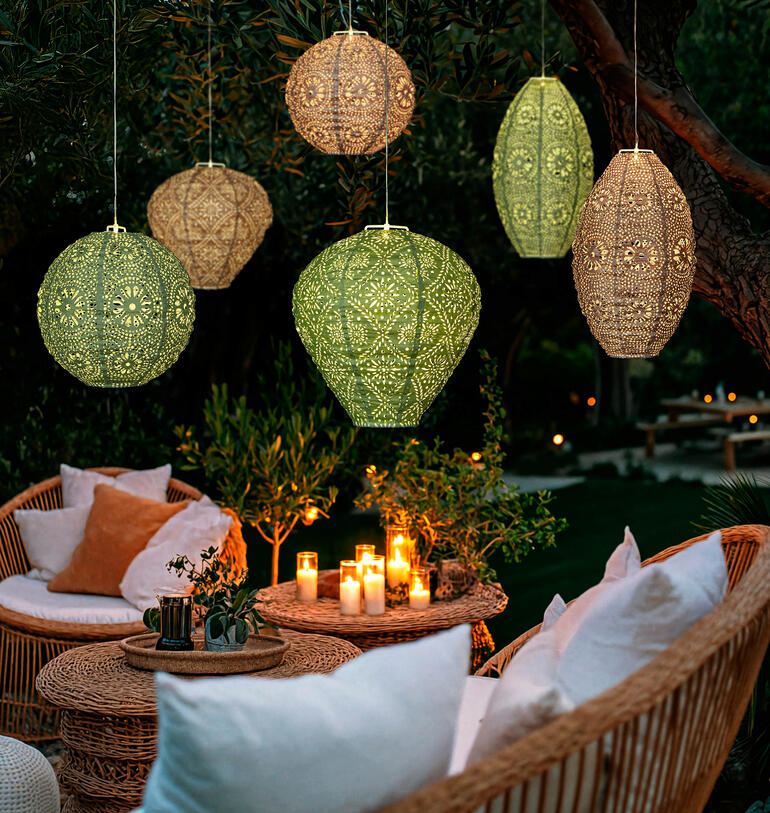 Zes weerbestendige lampions met zonne-energie en LED's rond een tuinlounge.