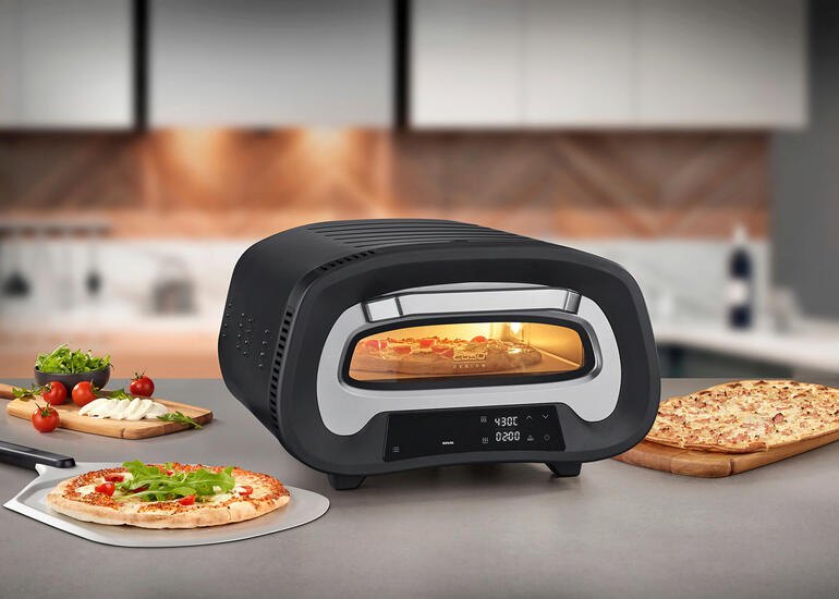 430 °C pizzaoven op een werkblad, omringd door ingrediënten