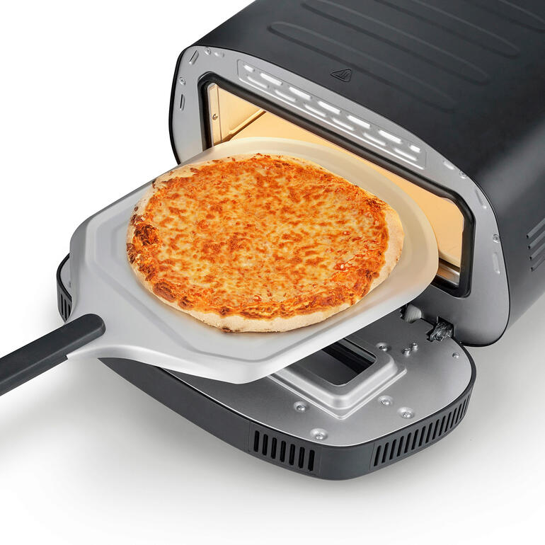 Pizza op een pizzaschep, wordt in de 430 °C pizzaoven geschoven