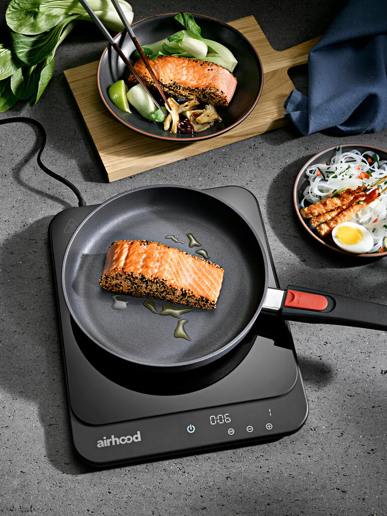 Ultradun inductiekookplaat met een pan en gebakken zalm.