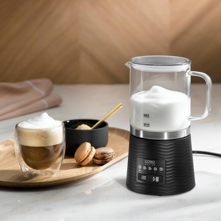 Design-melkopschuimer met melkschuim, koffie en macarons