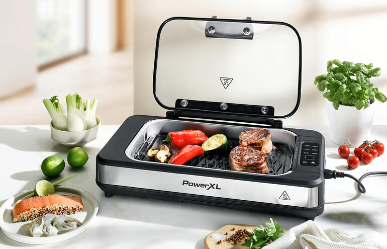 Tafelgrill met open deksel en groenten en vlees erop.