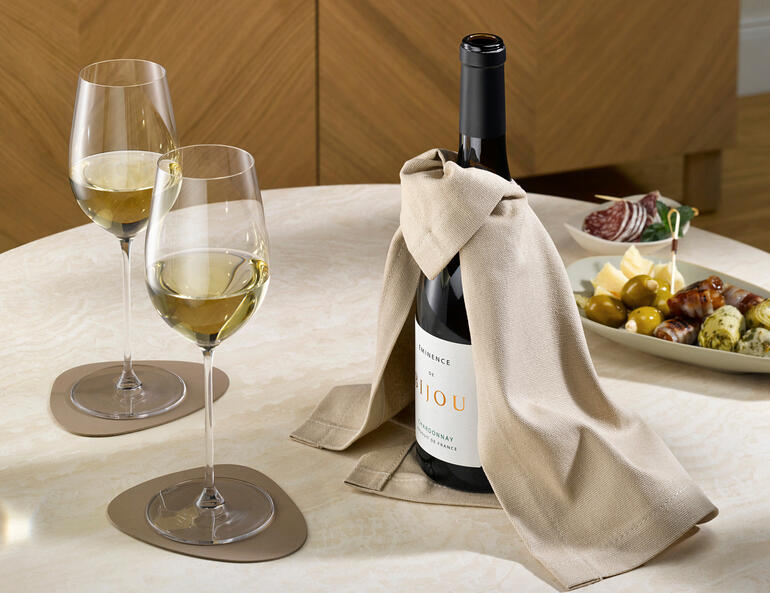Wijncape met een fles wijn en twee glazen op een tafel.