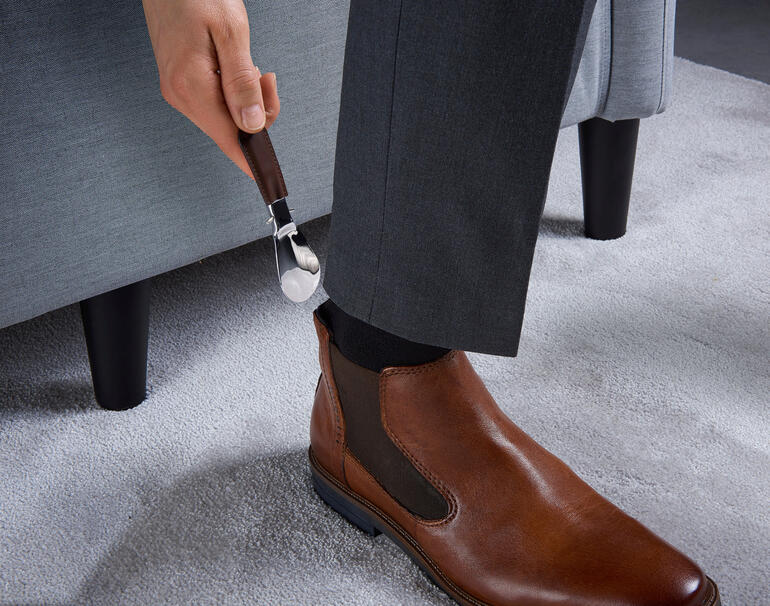 Persoon die een opvouwbare schoenenlichter van tuigleer gebruikt.