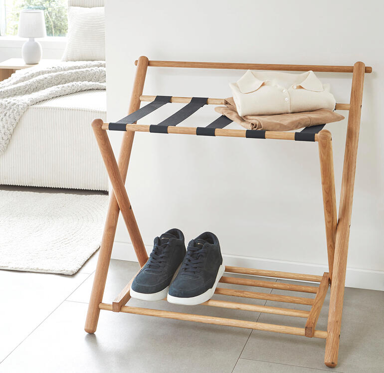 Eik kofferopslag met opgevouwen kleding en sneakers erop.