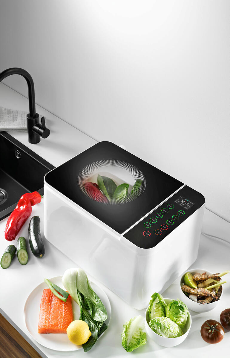 Food Washer-apparaat op aanrecht, omringd door verse groenten.