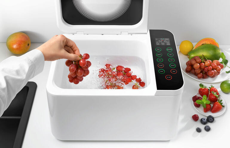 Leg er bijvoorbeeld fruit in en selecteer het bijbehorende programma. Vervolgens wordt het reinigingsproces gestart. Hand pakt druiven in de Food Washer terwijl het water borrelt.