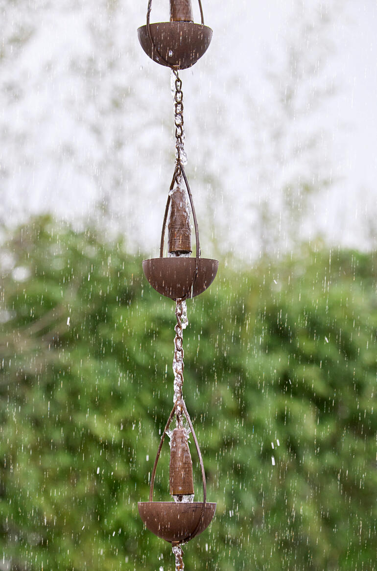 Het regenwater stroomt zachtjes langs de ketting naar beneden en geeft zo uw tuin een visueel en akoestisch effect. Detailweergave van een 3-in-1 regenketting met water dat uit de bekers stroomt.