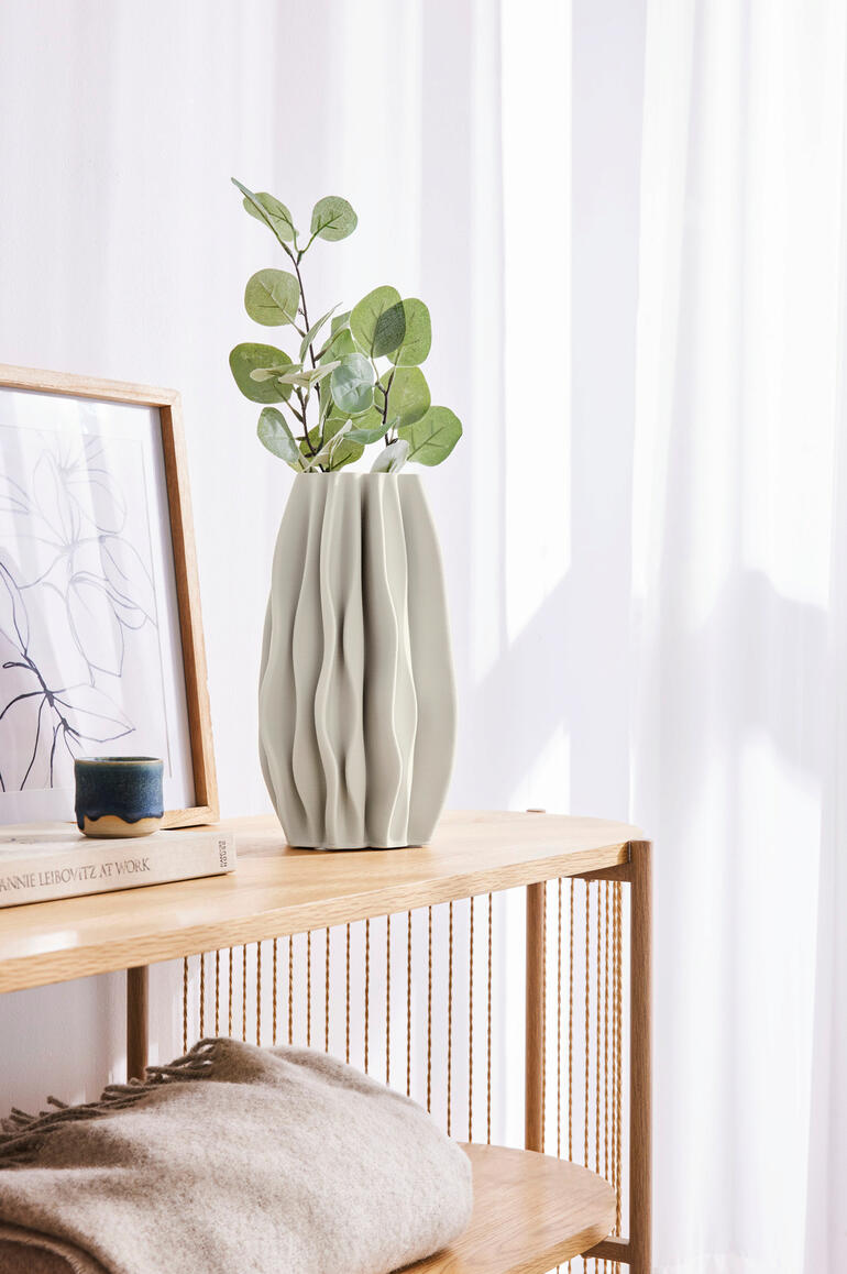 3D-geprinte keramische vaas met plant op een plank.