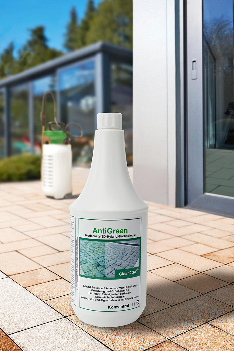 Fles AntiGreen, 1 liter concentraat op een bestrating