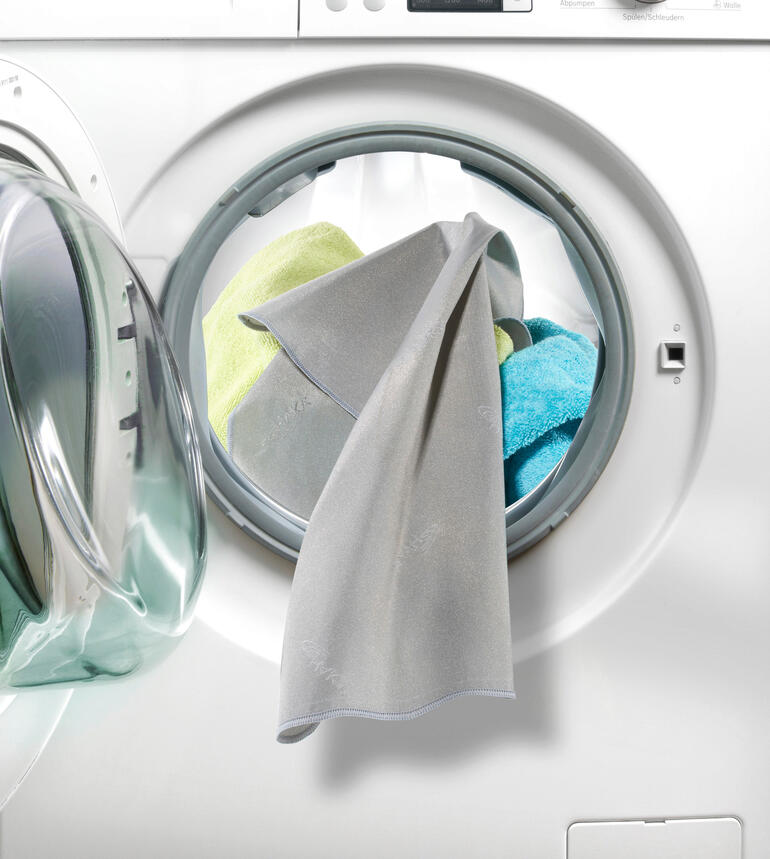 Actief zilver elimineert tot 99,9 % van de bacteriën op uw wasgoed. SilverWash®-Wasmachine doek hangt uit een wasmachine met kleurrijke doeken