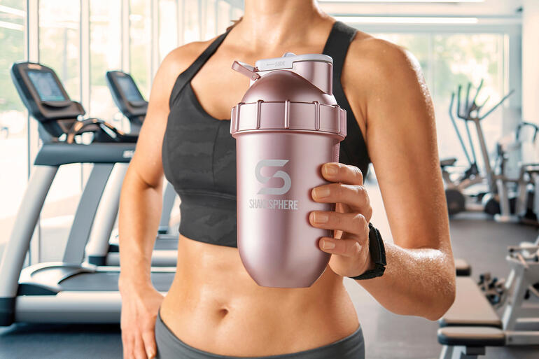 Vrouw houdt een roze shaker vast in een sportschool.
