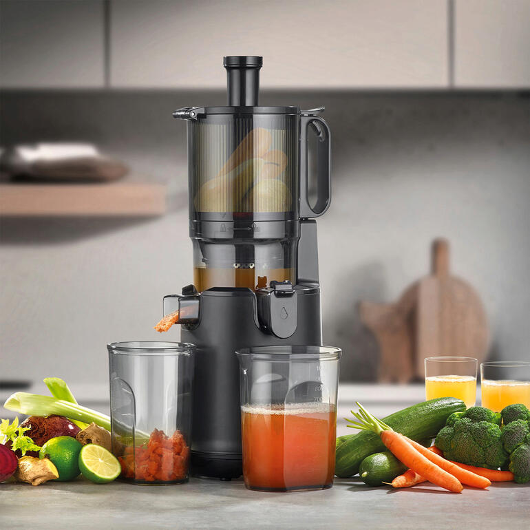 CASO Design Slow-Juicer met verse groenten en twee glazen sap op een tafel