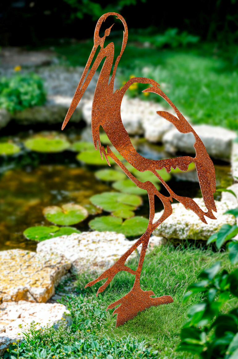 Tuinsteek in de vorm van een reiger van roestkleur in de tuin