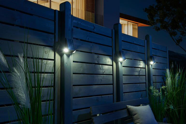 De set van 3 is ook geschikt voor het verlichten van grotere oppervlakken. Slimme solarstraler verlicht een houten schutting in de nacht.