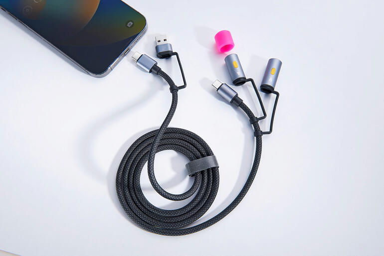 4-in-1 oplaadkabel met meerdere aansluitmogelijkheden op een tafel naast een smartphone.