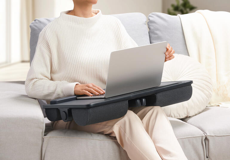 Persoon met een 2-in-1 laptopkussen op schoot dat als tafel fungeert.