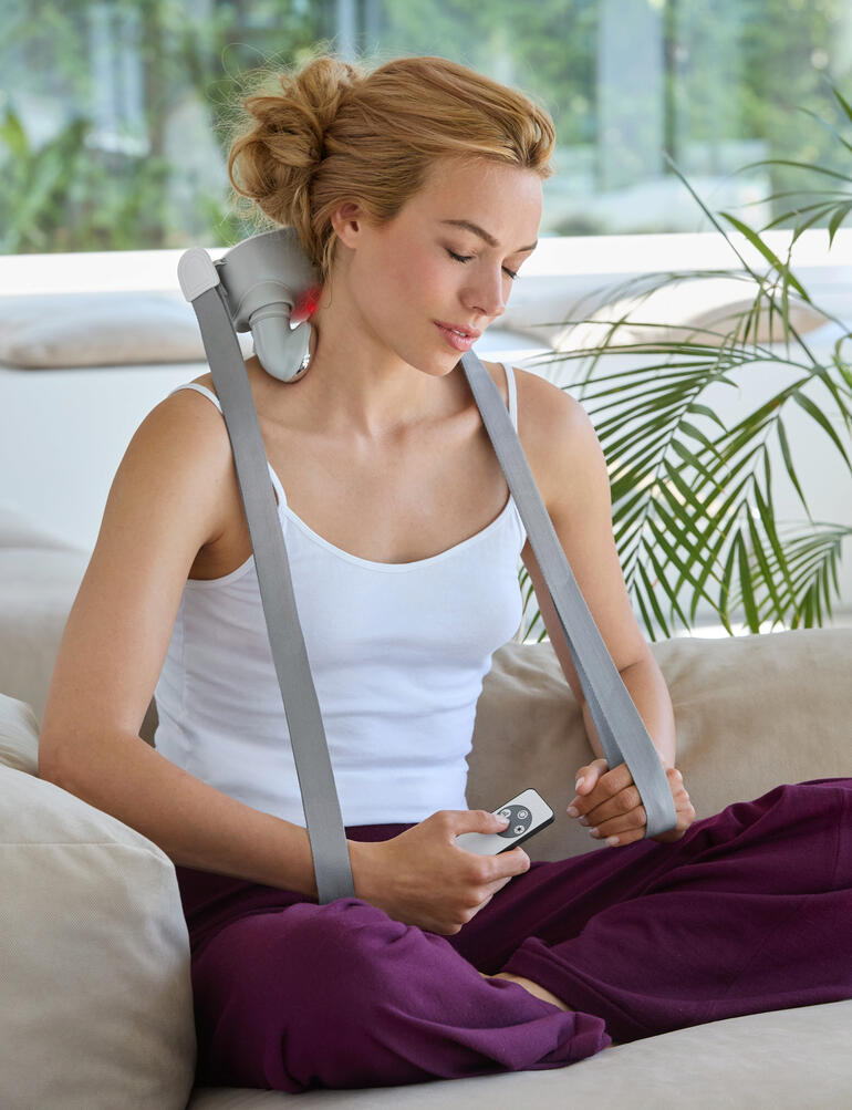 Vrouw gebruikt een 4-kops Shiatsu massager op de bank.
