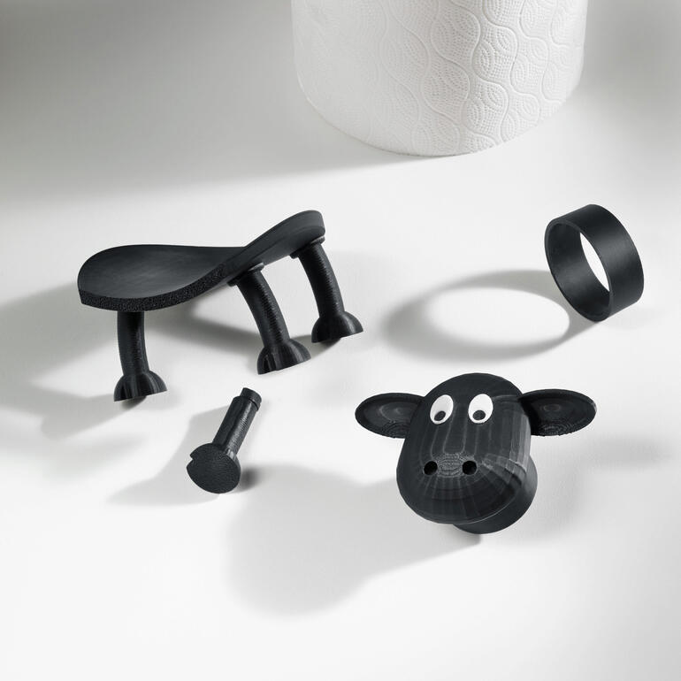 Volledig middels 3D-printen vervaardigd in Duitsland. Gescheiden onderdelen van een toiletpapierhouder in schapenontwerp op een tafel.