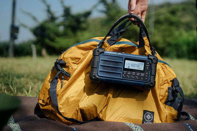 Man met gele tas, houdt de zwarte radio in zijn hand.