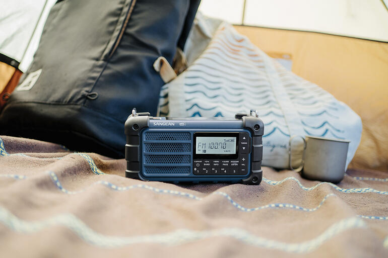 Radio op een deken, naast een kopje en een rugzak.