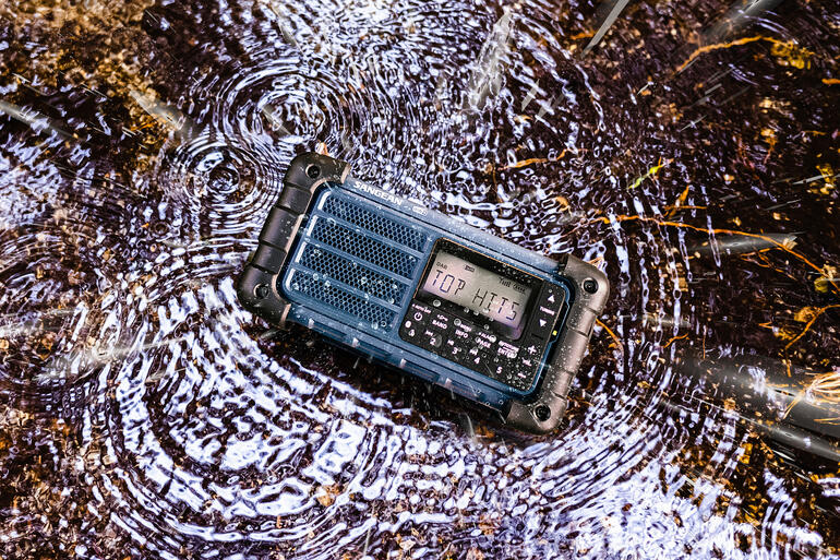 Radio ligt in een plas, waterdruppels eromheen.