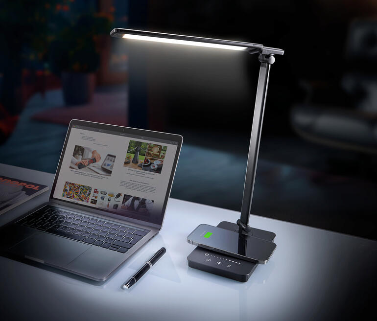 Dynamische LED-bureau lamp op een bureau naast een laptop