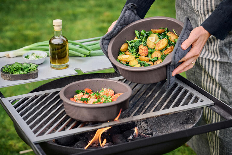 Keltentopf met groenten wordt van de grill gehaald.