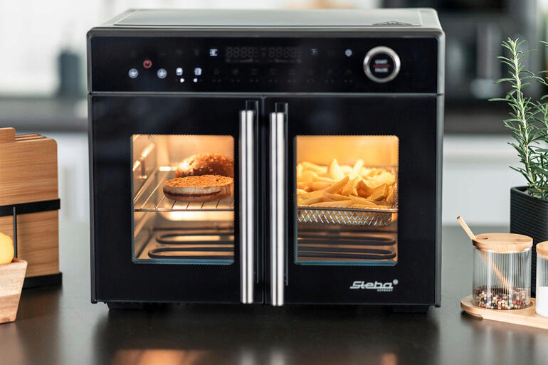 Airfry-grilloven Tri-Zone met open deuren en zichtbare frietjes.