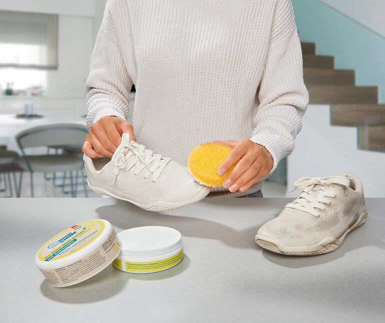 Ook ideaal om uw witte sneakers mee schoon te maken. Vrouw maakt witte schoenen schoon met een spons en universeelreiniger.