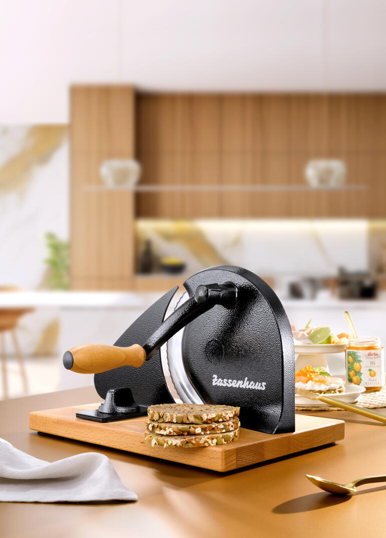 Handmatige broodsnijder op een houten plank met vers gesneden brood.