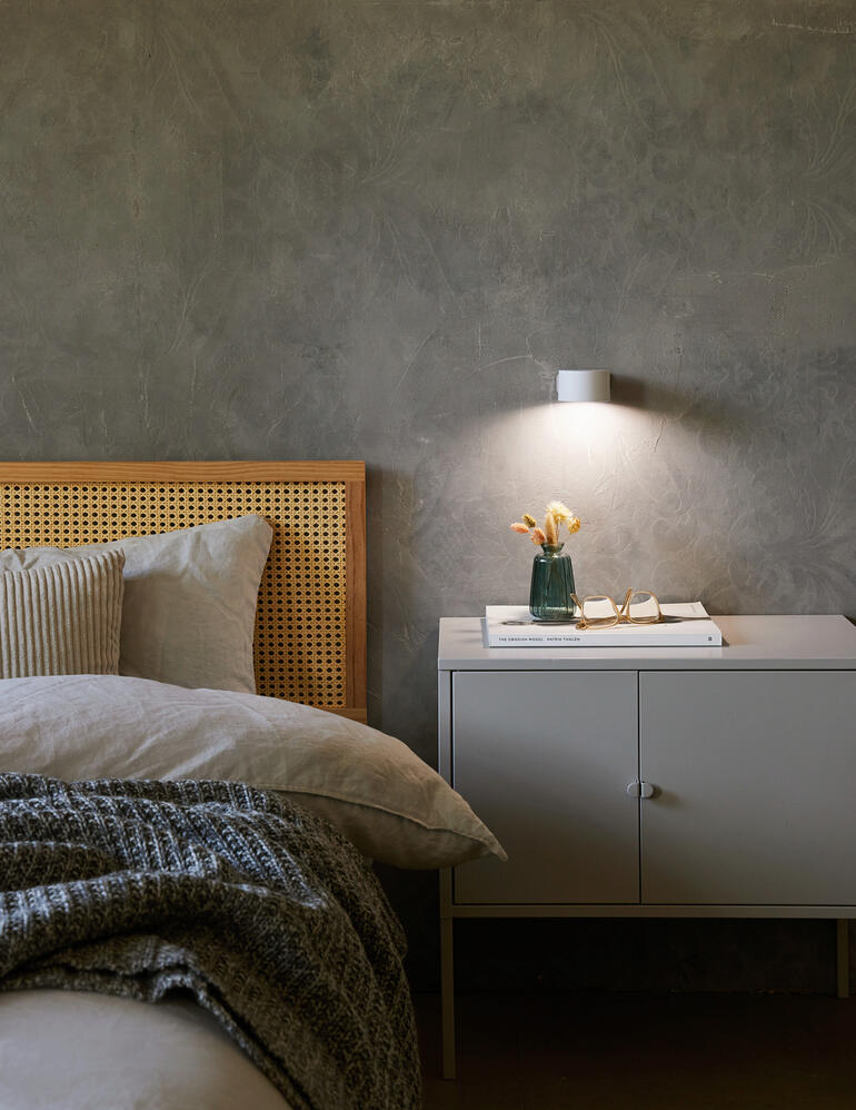 Ook geschikt als stijlvolle wandlamp of ... Accu-lamp aan de muur boven een nachtkastje met een vaas.