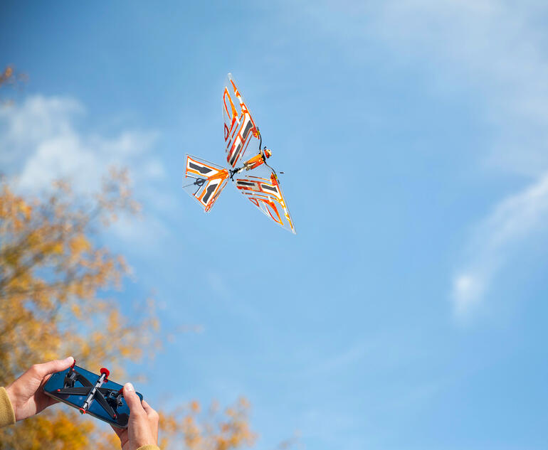 Ornithopter met afstandsbediening Afstandsbediende ornithopter vliegt door een blauwe lucht met een herfstachtergrond.
