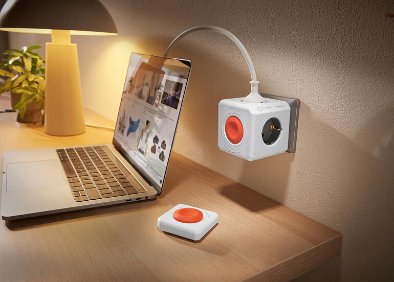 Tafel met laptop en PowerCube-stopcontact, bevestigd aan de muur.