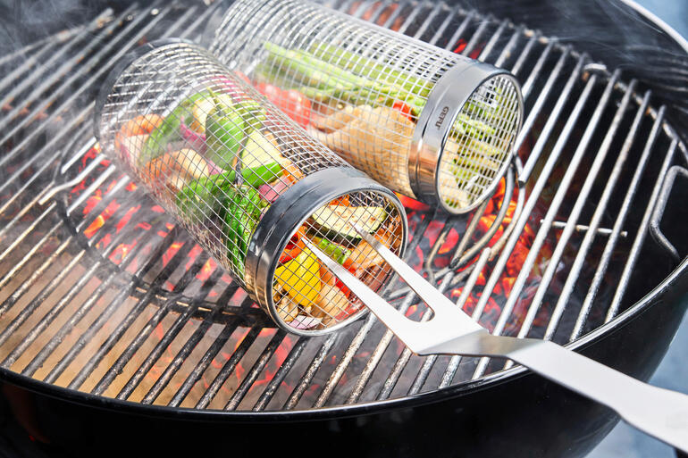 Grillmandje van metaal met groenten erin, op de grill met gloeiende kolen.